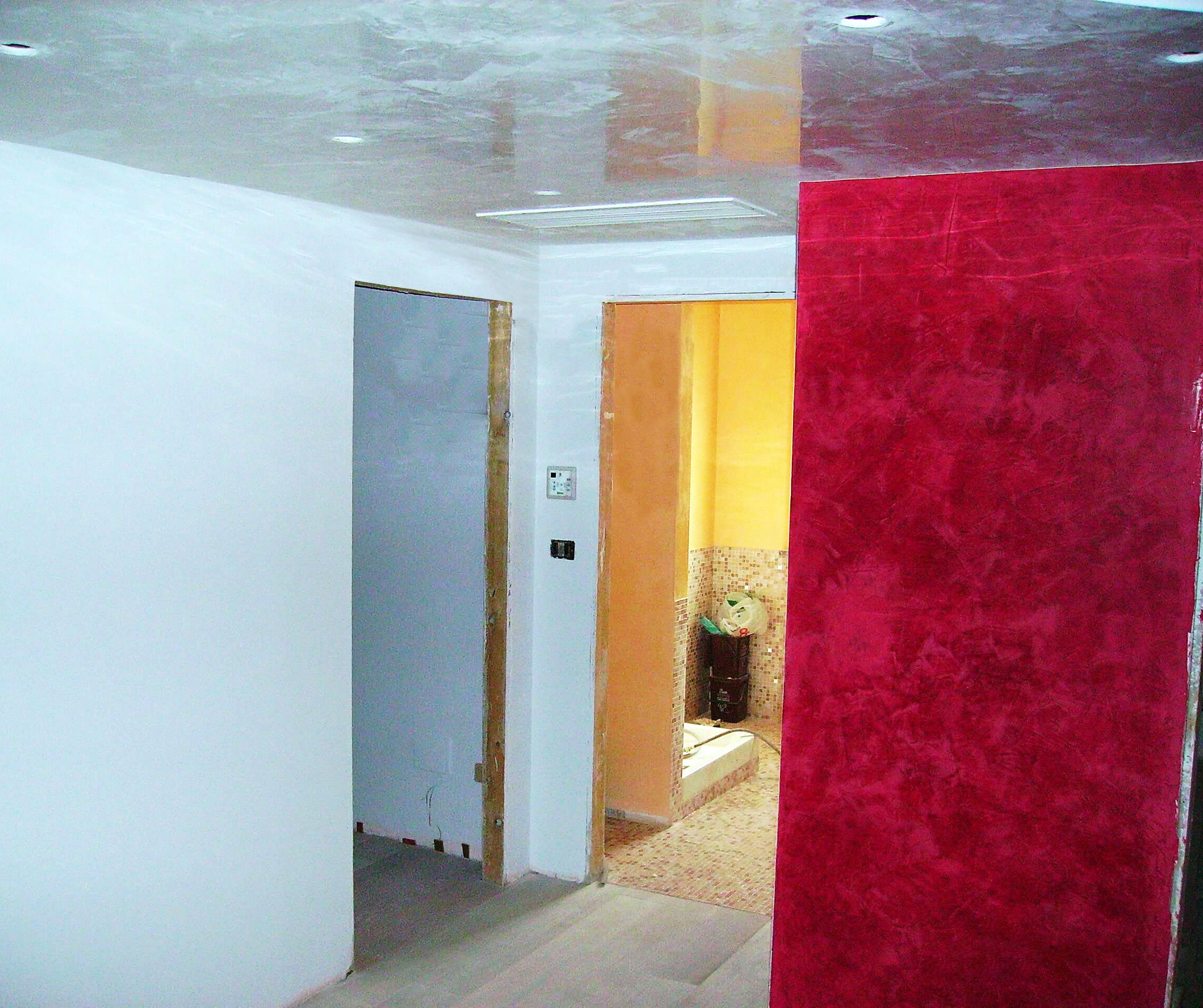 corridoio con parete rossa spatolata e soffitto lucido